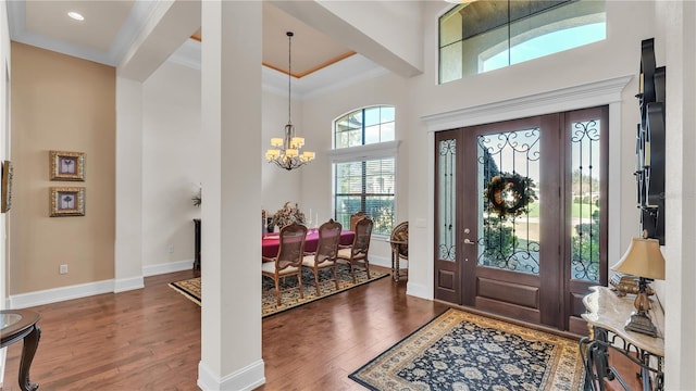 entrance foyer featuring ornamental molding, dark hardwood / wood-style floors, a chandelier, and a high ceiling