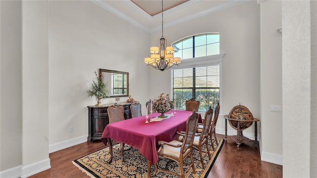 dining space featuring dark wood-type flooring, a towering ceiling, crown molding, and a notable chandelier