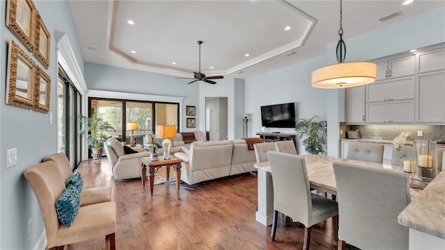 dining area with ceiling fan, dark hardwood / wood-style flooring, and a tray ceiling