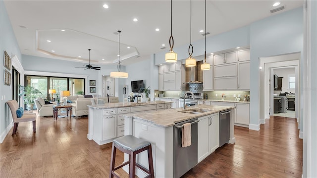 kitchen featuring white cabinetry, decorative light fixtures, a raised ceiling, a large island, and light stone countertops