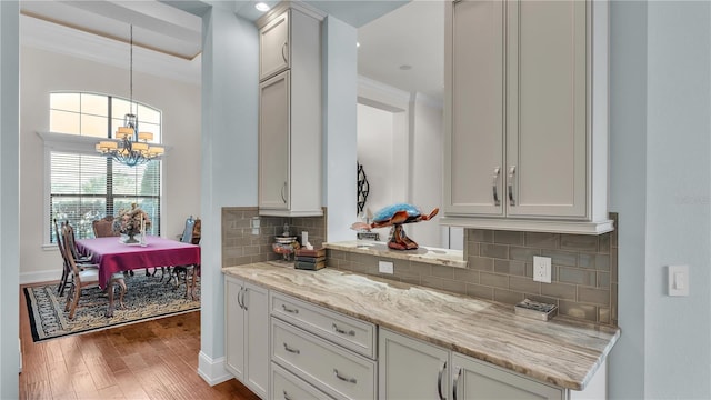 kitchen featuring hardwood / wood-style floors, light stone counters, white cabinets, decorative light fixtures, and a chandelier