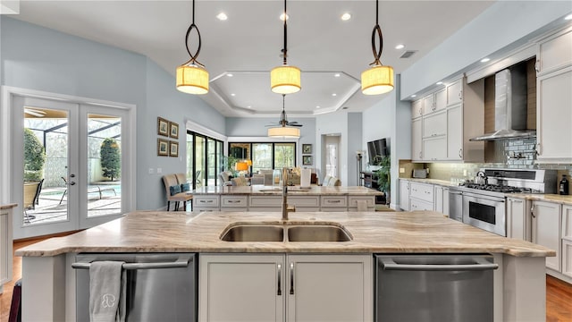 kitchen with white cabinetry, appliances with stainless steel finishes, wall chimney range hood, and decorative light fixtures