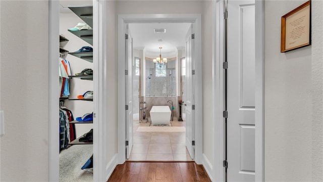 hallway with an inviting chandelier and light hardwood / wood-style flooring