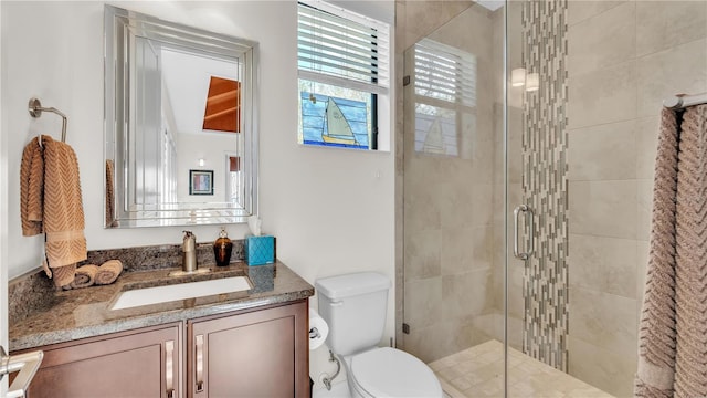 bathroom with vanity, a shower with door, and toilet