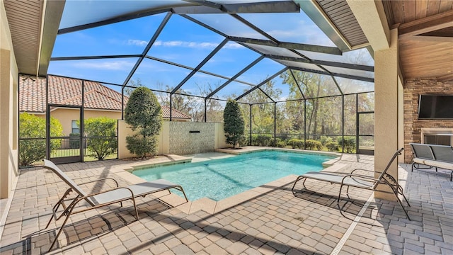 view of swimming pool featuring a lanai, a patio area, and an outdoor fireplace