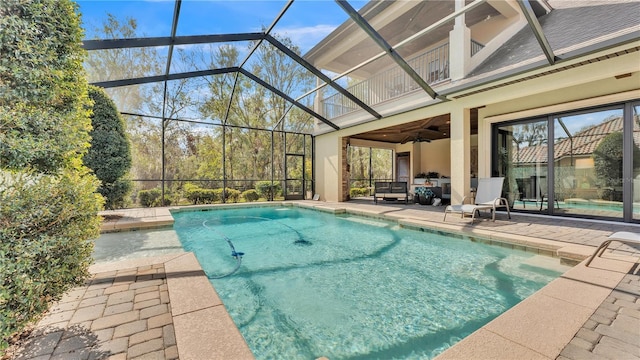 view of swimming pool with ceiling fan, a patio, and glass enclosure