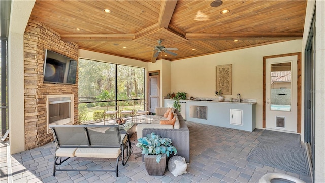 view of patio / terrace with ceiling fan, an outdoor kitchen, sink, and exterior fireplace