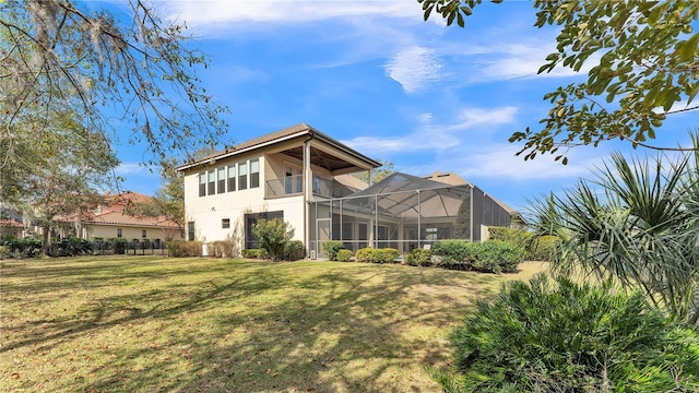 rear view of house featuring a balcony, a yard, and glass enclosure