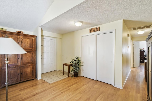 foyer entrance with light hardwood / wood-style flooring and a textured ceiling