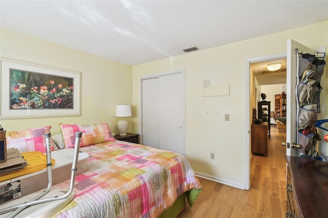 bedroom featuring light hardwood / wood-style flooring, a closet, and a textured ceiling