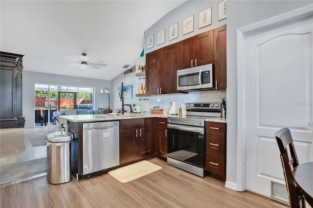 kitchen featuring decorative backsplash, light stone counters, kitchen peninsula, stainless steel appliances, and light hardwood / wood-style flooring