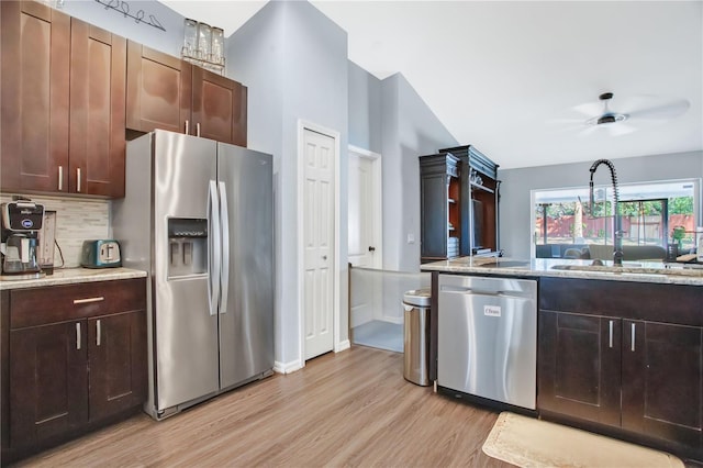 kitchen with sink, light stone counters, appliances with stainless steel finishes, light hardwood / wood-style floors, and backsplash