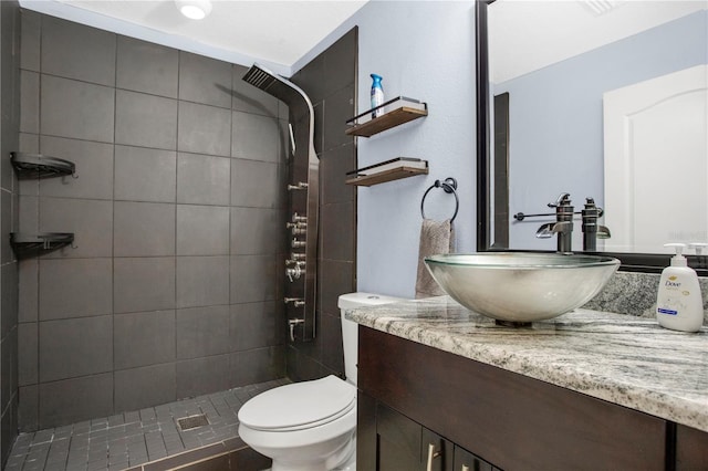 bathroom with vanity, toilet, and a tile shower