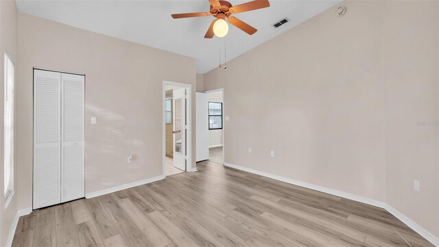 unfurnished bedroom featuring vaulted ceiling, multiple windows, light hardwood / wood-style floors, and a closet