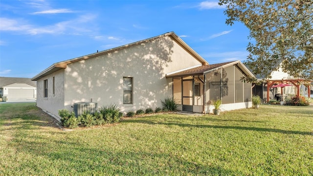 rear view of property with a sunroom, central air condition unit, and a lawn