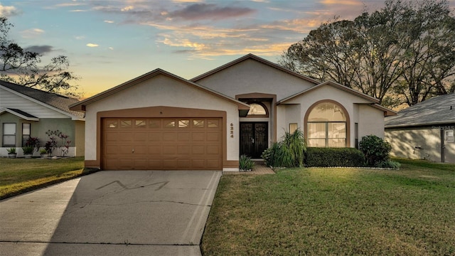 ranch-style house with a garage and a lawn