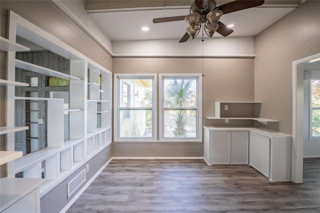 kitchen with a wealth of natural light, white cabinets, and light hardwood / wood-style flooring