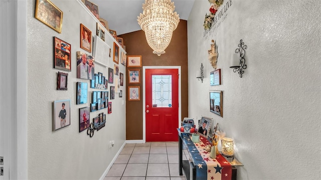 entrance foyer featuring a chandelier, a textured wall, light tile patterned floors, and baseboards