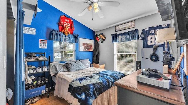 bedroom featuring ceiling fan, multiple windows, vaulted ceiling, and wood finished floors