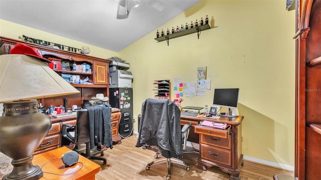 home office with a ceiling fan, light wood-type flooring, vaulted ceiling, and baseboards