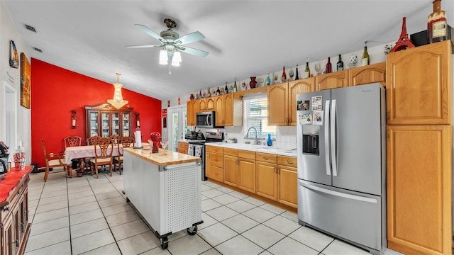 kitchen featuring vaulted ceiling, stainless steel appliances, light tile patterned flooring, and a sink