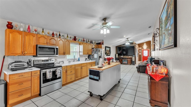 kitchen featuring stainless steel appliances, lofted ceiling, open floor plan, and light countertops