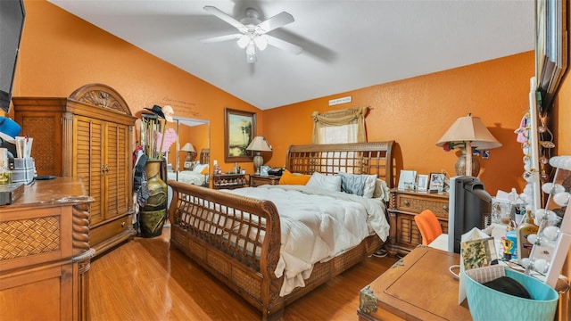 bedroom featuring a ceiling fan, lofted ceiling, a textured wall, and wood finished floors