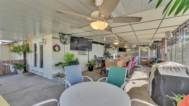 view of patio with outdoor dry bar, area for grilling, fence, and a ceiling fan