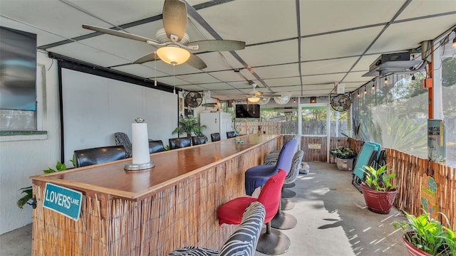 view of patio / terrace featuring exterior bar, ceiling fan, and fence