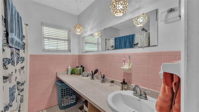 full bathroom with a wainscoted wall, tile patterned flooring, a textured ceiling, vanity, and tile walls