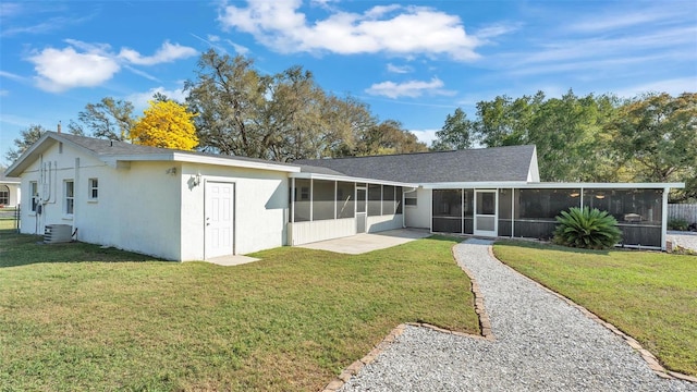 rear view of house with central air condition unit, a sunroom, a patio area, and a lawn