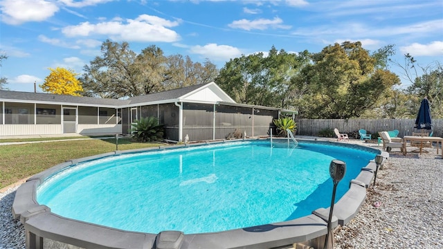 view of swimming pool featuring a sunroom, a lawn, fence, and a fenced in pool