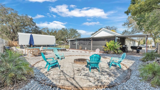 view of yard featuring a sunroom, fence, and a fire pit