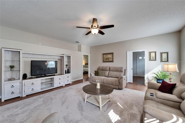 living room featuring ceiling fan, hardwood / wood-style floors, and a textured ceiling