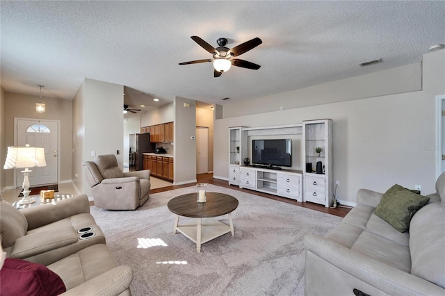 living room featuring ceiling fan, a textured ceiling, and light wood-type flooring