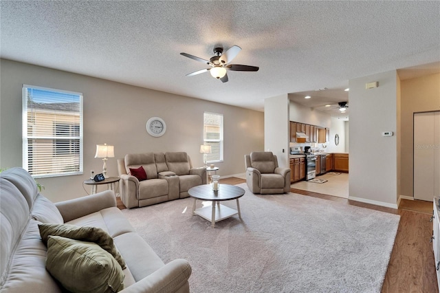 living room featuring a textured ceiling, ceiling fan, and light wood-type flooring