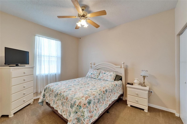 carpeted bedroom featuring ceiling fan and a textured ceiling