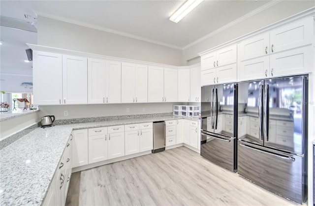 kitchen featuring ornamental molding, black refrigerator, white cabinets, and light stone counters