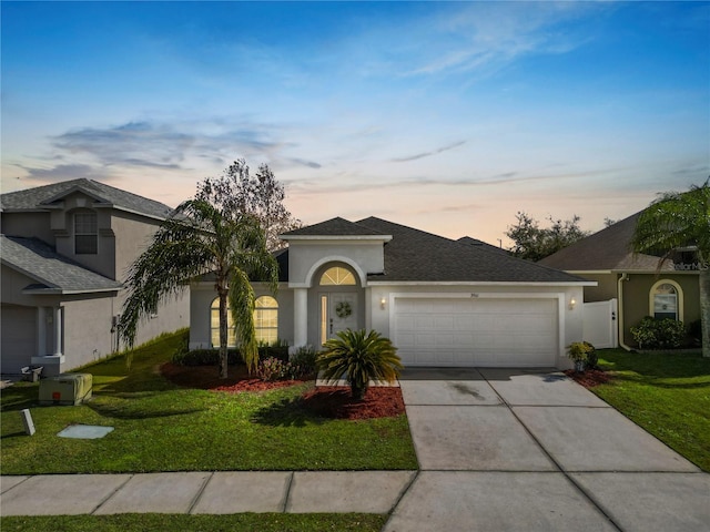 ranch-style house featuring a garage and a lawn