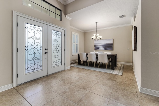 entryway with crown molding, an inviting chandelier, french doors, and light tile patterned floors