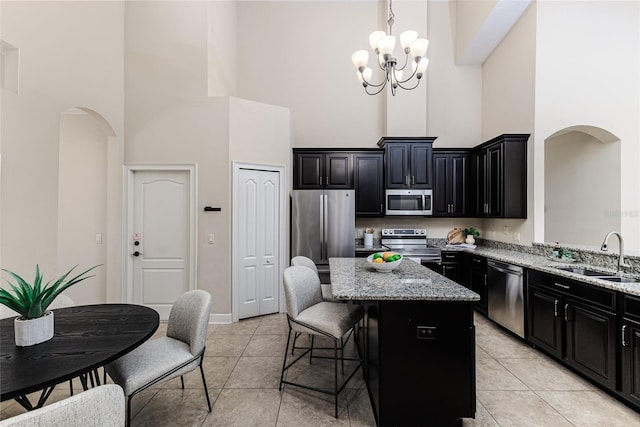 kitchen with a kitchen bar, sink, light stone counters, a kitchen island, and stainless steel appliances