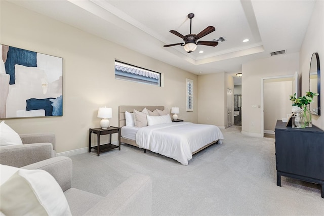 bedroom with a raised ceiling, ceiling fan, carpet floors, and ensuite bath