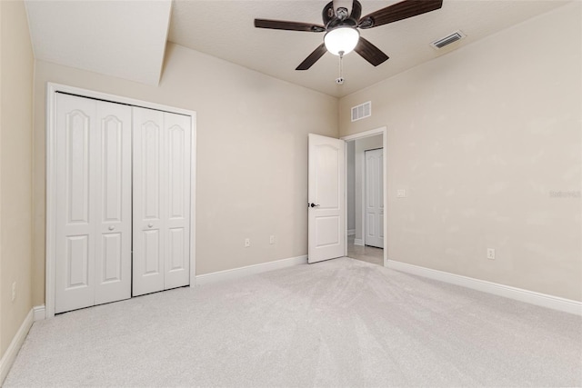 unfurnished bedroom featuring a textured ceiling, light colored carpet, a closet, and ceiling fan