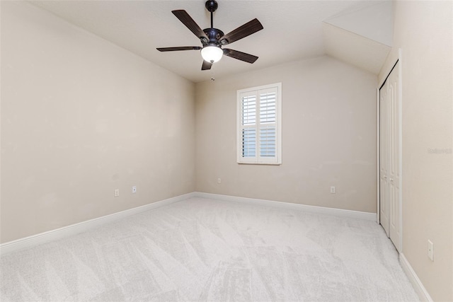 unfurnished bedroom featuring ceiling fan, light colored carpet, vaulted ceiling, and a closet