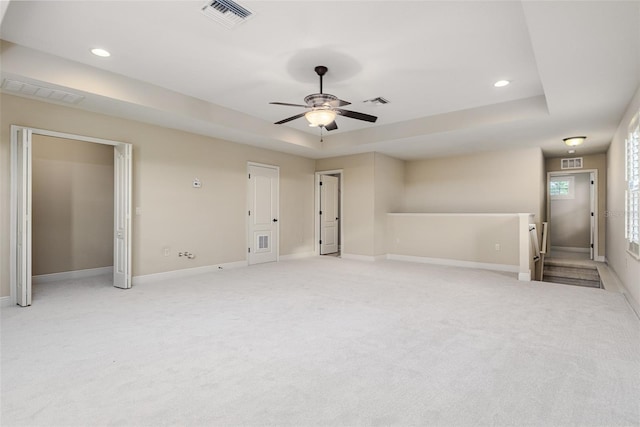 carpeted spare room featuring ceiling fan and a raised ceiling