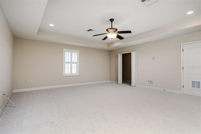 carpeted empty room featuring a raised ceiling and ceiling fan