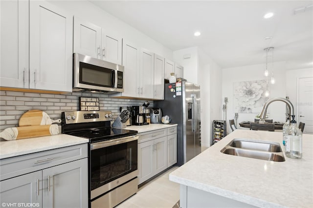 kitchen featuring pendant lighting, sink, gray cabinetry, stainless steel appliances, and decorative backsplash