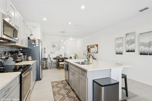 11658 Bluestone Ct, Parrish, FL 34219 - kitchen featuring a sink, stainless steel appliances, gray cabinetry, a kitchen bar, and an island with sink
