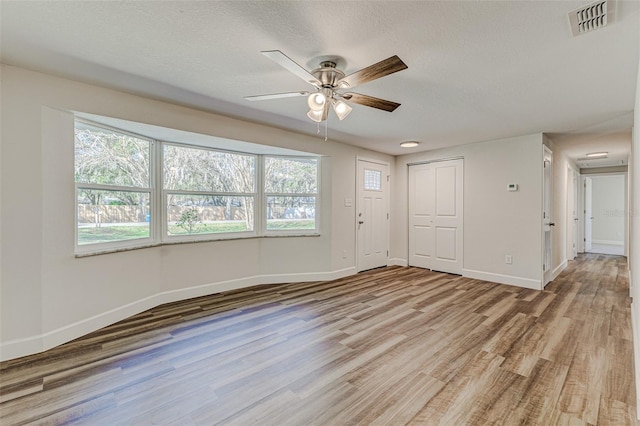 unfurnished room with ceiling fan, light hardwood / wood-style floors, and a textured ceiling