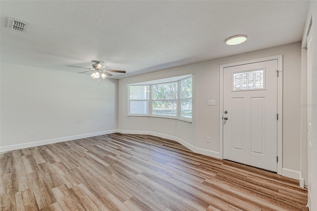 entrance foyer with ceiling fan, a textured ceiling, and light wood-type flooring